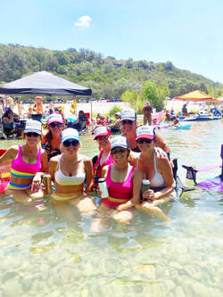 Women swimming wearing hats and drink holders while at the Frio River