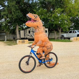 TRex Riding a Bike at Andy's RV park on River Road
