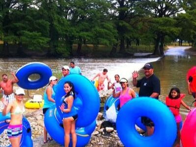 People standing with inner tubes on the edge of the Frio River in Concan Texas